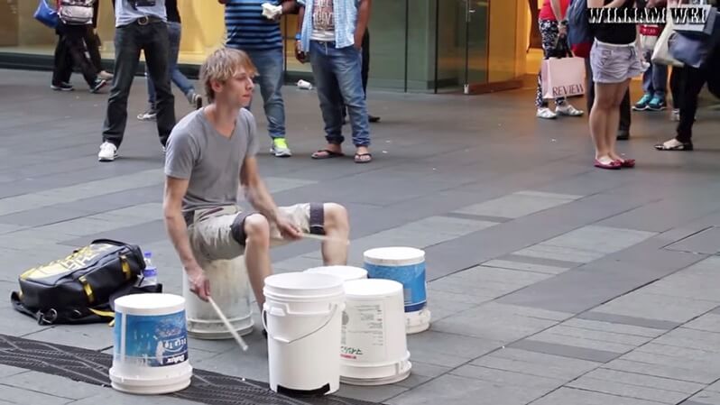 バケツでストリートドラムをする男性